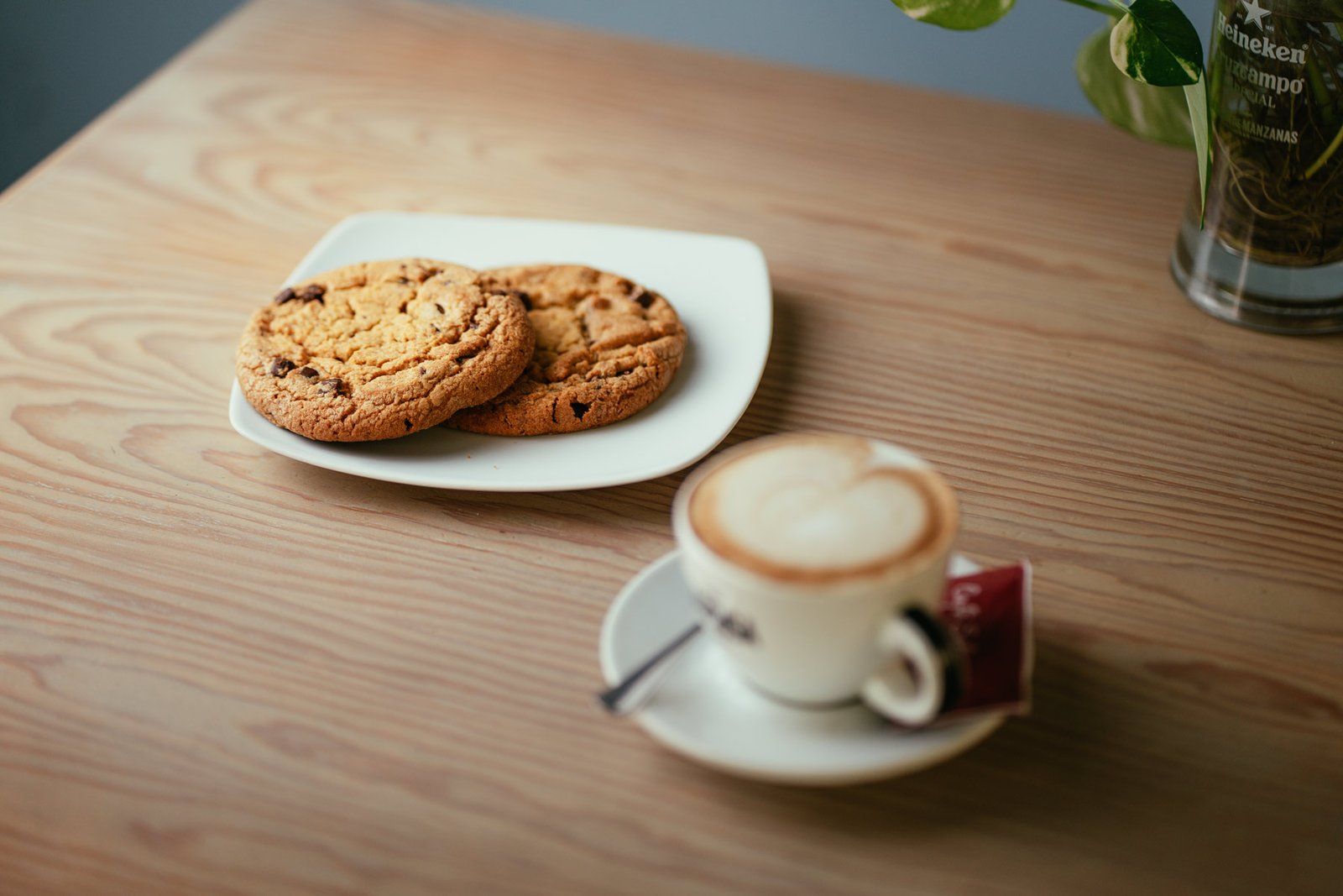 Galletas con chips de chocolate y un capuchino sobre una mesa de madera