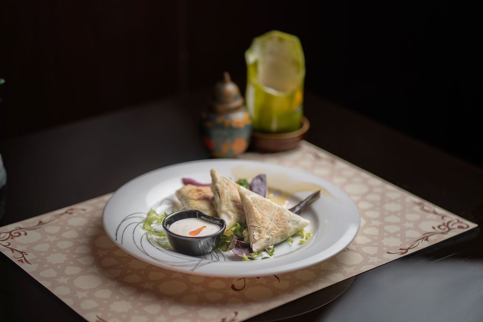 Plato con triángulos de masa y salsa sobre un mantel estampado